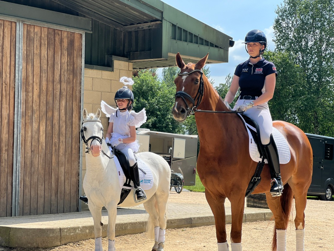Young rider with angel wings alongside professional equestrian